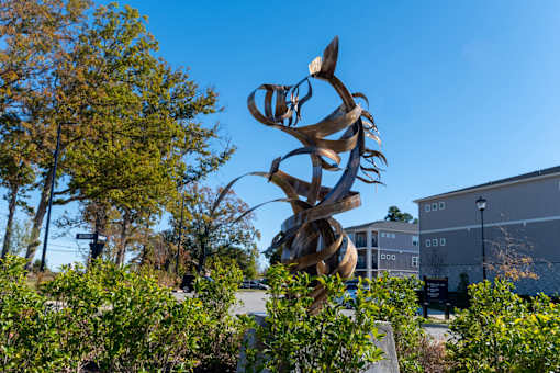 A large, abstract sculpture of twisted metal is the focal point of this image.