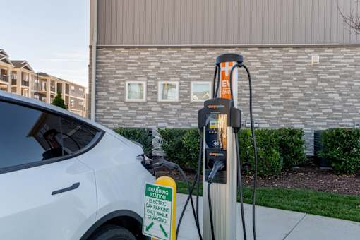 A white car is plugged into an electric car charging station.