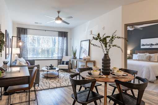 A dining room with a table set for two and a bed in the background.
