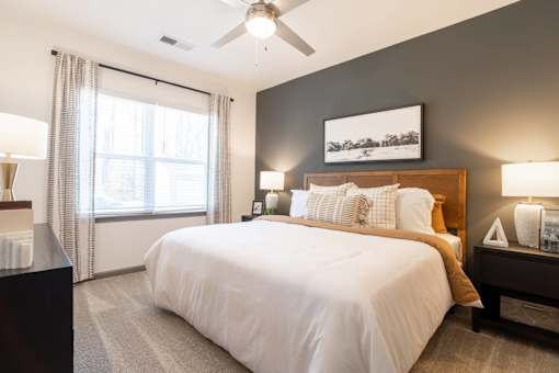 A bedroom with a large bed and a ceiling fan.