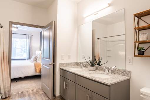 A bathroom with a double sink vanity and a mirror above it.