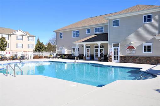 A swimming pool in front of a building with a red and white sign.