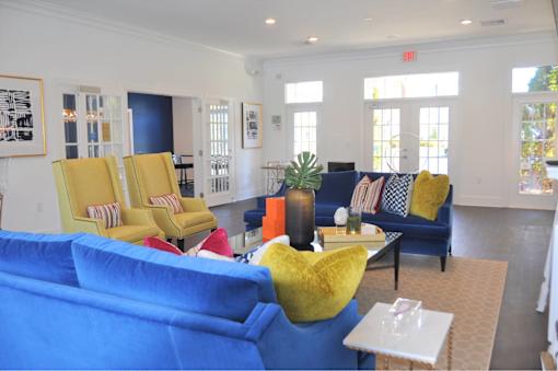 A living room with blue couches and yellow chairs.