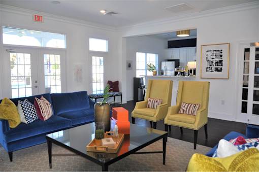 A living room with a blue couch, yellow chairs, and a coffee table.