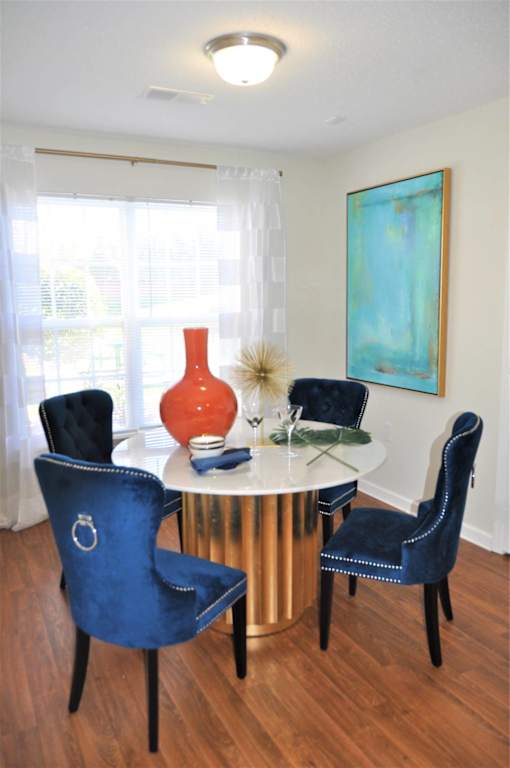 A dining room with a round table and blue chairs.