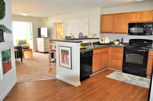A kitchen with black appliances and wooden cabinets.