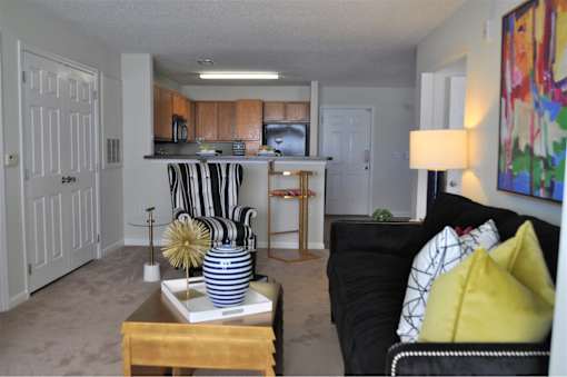 A living room with a black couch and a coffee table with a striped vase on it.