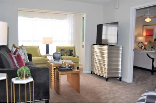 A living room with a black couch, a yellow chair, a wooden coffee table, and a television.