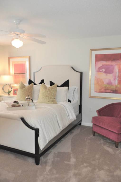 A bedroom with a white bed and a pink chair.