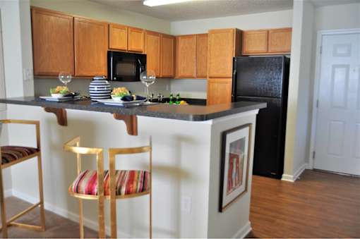 A kitchen with a black refrigerator and wooden cabinets.