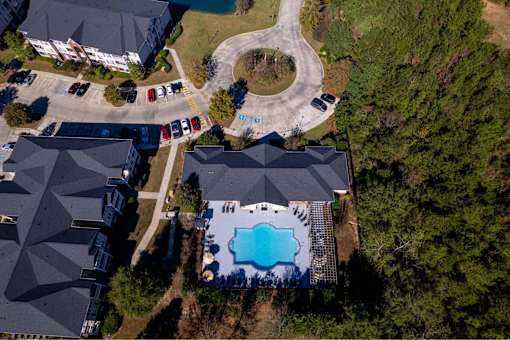 A bird's eye view of a residential area with houses, cars, and a swimming pool.