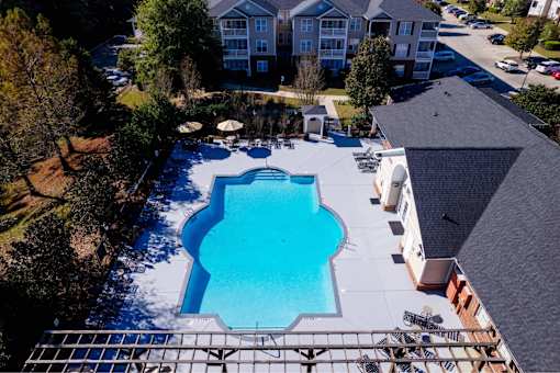 A large swimming pool surrounded by a metal fence and a few trees.