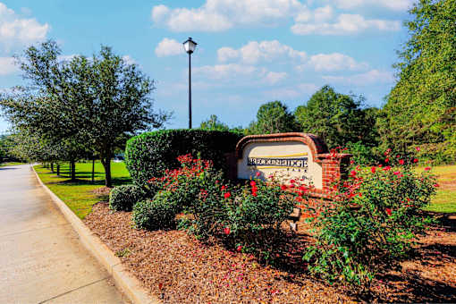 A sign that says "Historic Riverside" is surrounded by red flowers and green bushes.