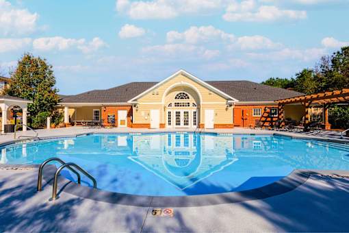 A large swimming pool in front of a building with a yellow roof.
