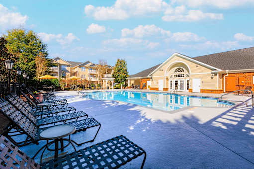 A pool area with chairs and a building in the background.