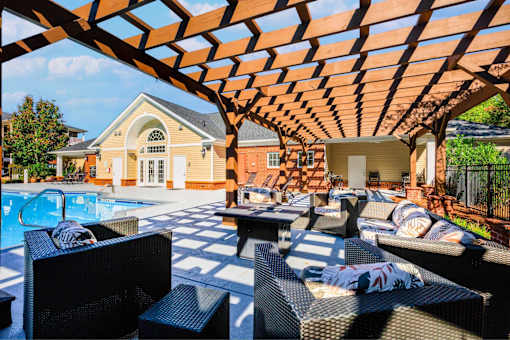 A poolside patio with a black wicker chair and a black table.