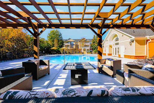 A patio with a pool and a wooden pergola.