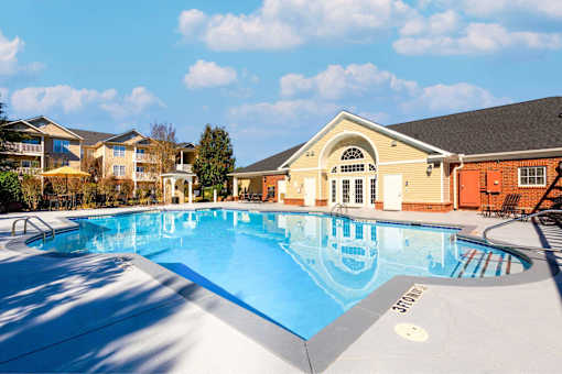 A large outdoor swimming pool with a slide and a building in the background.