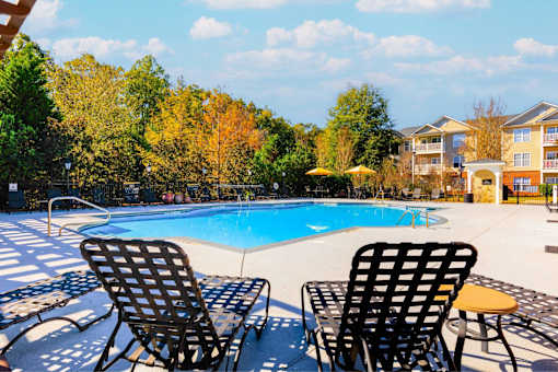 Two chairs are placed on a patio by a pool.