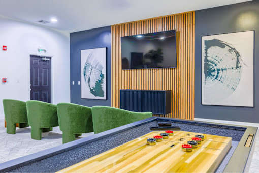 A game of air hockey is set up in a room with green chairs and artwork on the wall.