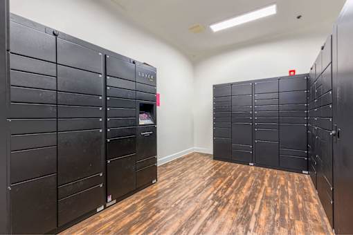 A room with black lockers and wooden floors.