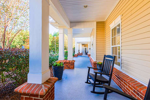 A porch with a bench and a chair.