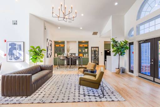 A large, modern living room with a grey sofa, a green armchair, and a patterned rug.