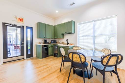 A kitchen with green cabinets and a dining table with chairs.
