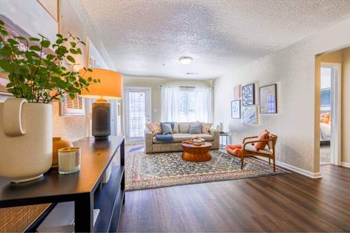 A living room with a couch, a chair, a potted plant, and pictures on the wall.
