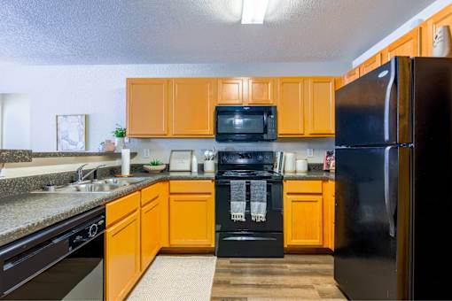 A kitchen with black appliances and orange cabinets.
