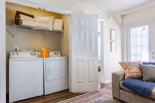 A laundry room with a washer and dryer and a couch in the living room.