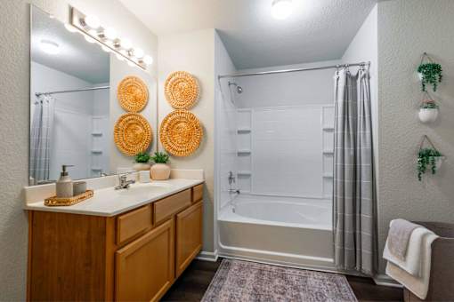 A bathroom with a white tub and wooden vanity.