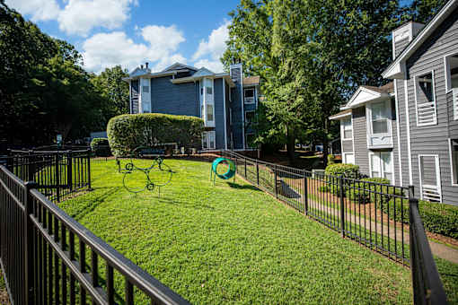 A black fence surrounds a green lawn with a playground in the middle.