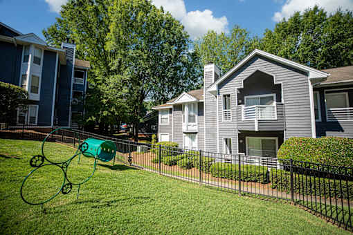 A playground with a green slide in the foreground and apartment buildings in the background.