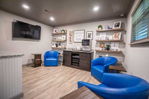 A room with blue chairs and a television mounted on the wall.