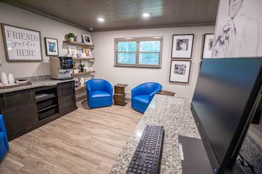 A room with a desk, chairs, and a computer.