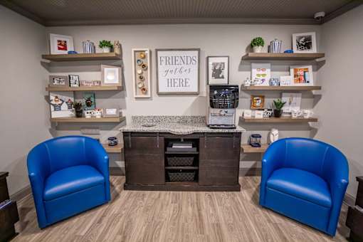 A waiting room with two blue chairs and a sign that says "Friends are here".