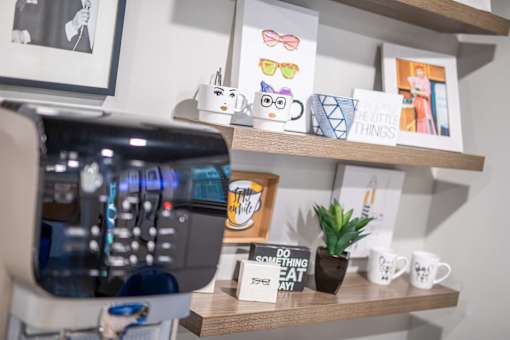 A coffee machine is on the left with a shelf above it holding a sign that says "Do something nice today" and a small potted plant.