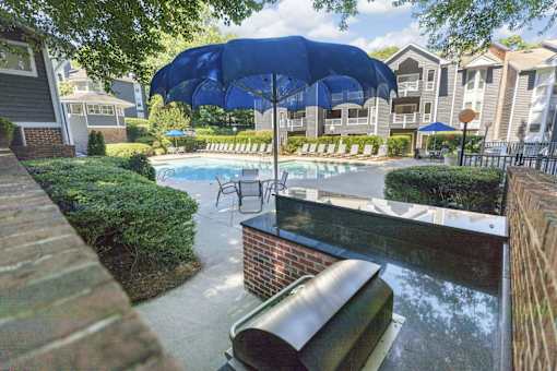 A pool area with a blue umbrella and a brick wall.