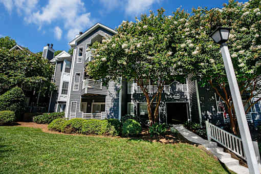 A grey house with a white fence in front.