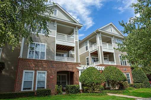 A two-story building with a red brick base and beige upper floors with balconies.