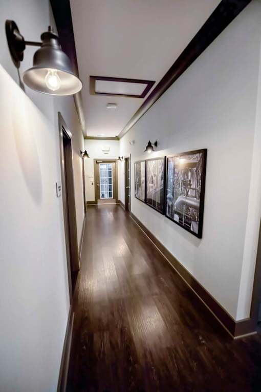 A long hallway with pictures on the wall and a light on.