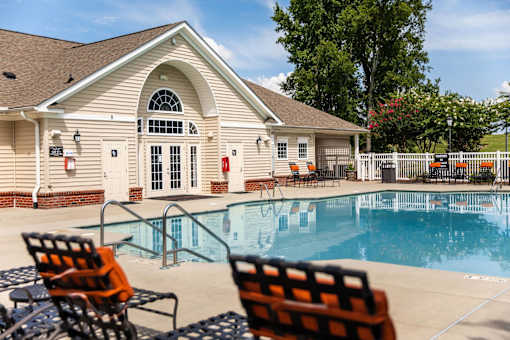 A poolside scene with a building and chairs.