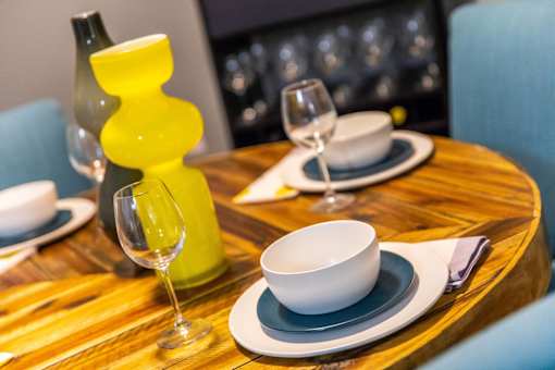 A table set with a yellow vase, white bowl, and glasses.