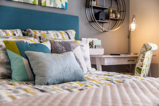 A bed with a blue headboard and a white bedspread with yellow and blue pillows.