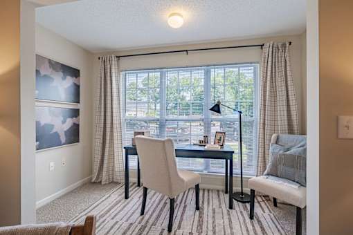 A room with a table, chairs, and a window with curtains.