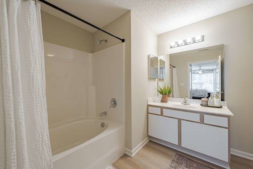 A white bathroom with a tub, sink, and mirror.