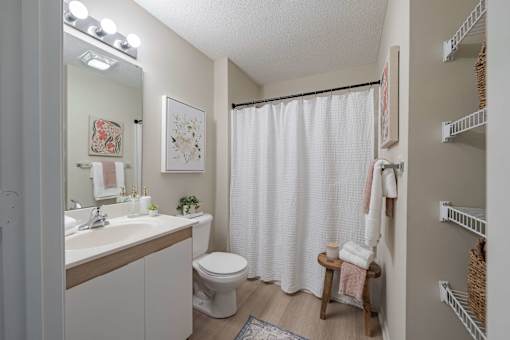 A white bathroom with a toilet, sink, and shower curtain.