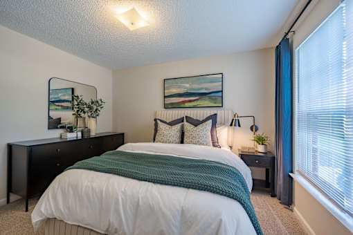 A bedroom with a large bed and a painting on the wall.