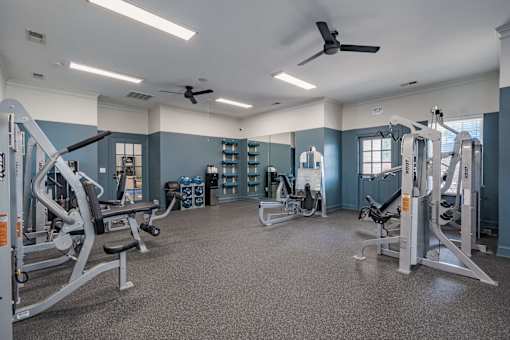 A spacious gym with a variety of equipment and a ceiling fan.